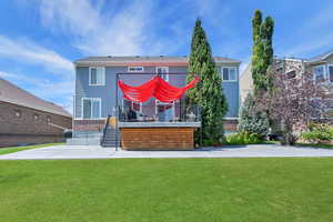 Rear view of house featuring a wooden deck, a yard, and brick siding