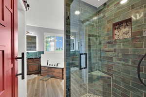 Bathroom featuring vanity, a garden tub, a shower stall, and wood finish floors
