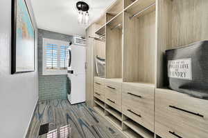 Walk in closet featuring stacked washer and dryer and wood finish floors