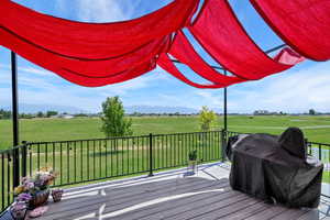 Wooden deck featuring a view of countryside, a yard, and a grill