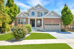 Craftsman-style home with covered porch, driveway, board and batten siding, an attached garage, and a front yard