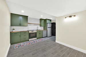 Kitchen featuring green cabinets, stainless steel appliances, decorative backsplash, recessed lighting, and a textured ceiling
