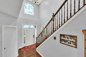 Foyer with a high ceiling, plenty of natural light, dark wood-style floors, and hanging lights