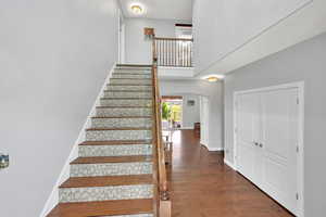 Stairs featuring arched walkways, a high ceiling, and hardwood / wood-style floors