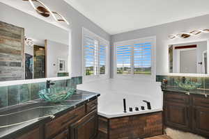 Full bath featuring a bath, two vanities, and decorative backsplash