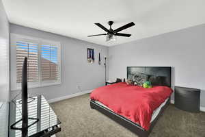 Carpeted bedroom with baseboards and a ceiling fan