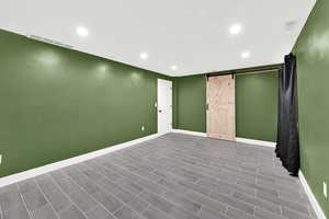 Below grade area with a barn door, recessed lighting, and wood finish floors