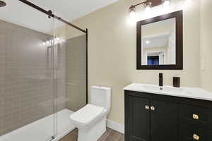 Full bath featuring vanity, a shower stall, and wood finish floors