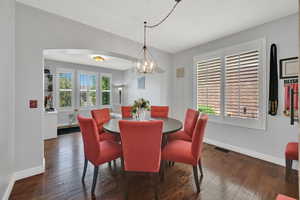 Dining room featuring arched walkways, hardwood / wood-style floors, and a chandelier