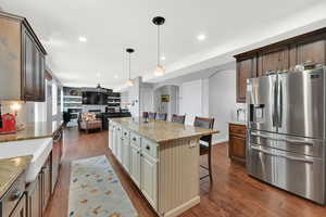Kitchen featuring stainless steel appliances, a breakfast bar area, open floor plan, light stone countertops, and decorative backsplash