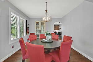 Dining space with arched walkways, wood finished floors, and suspended lighting