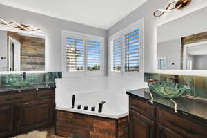 Full bath with two vanities, a bath, and decorative backsplash