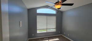 Unfurnished room featuring ceiling fan and dark colored carpet