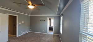 Carpeted spare room featuring crown molding, ceiling fan, and vaulted ceiling