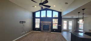 Unfurnished living room with ceiling fan, a fireplace, dark carpet, a high ceiling, and dark tile patterned floors