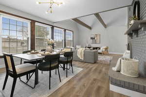 Dining space with wood finished floors, a fireplace, suspended lighting, and lofted ceiling with beams