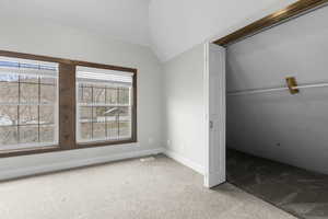 Unfurnished bedroom with light carpet, lofted ceiling, and a closet