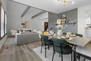 Dining space with light wood-type flooring, vaulted ceiling with beams, and suspended lighting