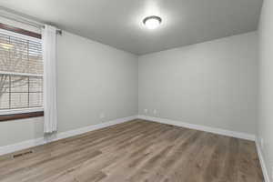 Empty room with light wood-type flooring and a textured ceiling