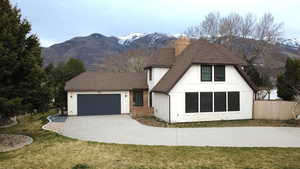 View of front of home featuring a mountain view, an attached garage, driveway, and a chimney