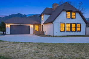 View of front of property with a shingled roof, an attached garage, concrete driveway, board and batten siding, and a front yard