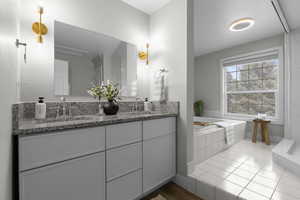 Full bath featuring double vanity, a bath, and light wood-type flooring