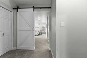 Corridor featuring light carpet and a barn door