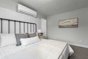 Carpeted bedroom with a wall mounted mini split and a textured ceiling