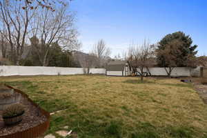 Fenced backyard featuring a shed