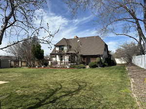 Back of property featuring a fenced backyard, a wooden deck, a chimney, and a shingled roof