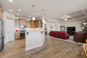 Kitchen featuring a kitchen bar, arched walkways, open shelves, open floor plan, and stainless steel appliances
