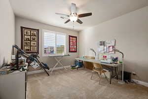 Home office with light colored carpet and ceiling fan