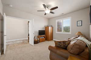 Living room featuring light carpet and a ceiling fan