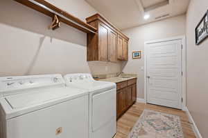 Laundry room with washing machine and dryer, light wood-type flooring, cabinet space, and recessed lighting