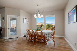 Dining room with light wood-type flooring, a mountain view, suspended lighting, and plenty of natural light
