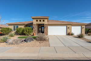 Prairie-style home featuring stucco siding, an attached garage, stone siding, and concrete driveway