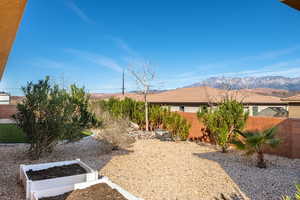 Fenced yard with a mountain view and a vegetable garden