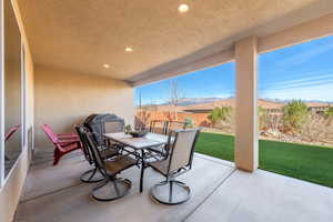 Fenced backyard featuring outdoor dining space, a patio, a mountain view, and grilling area