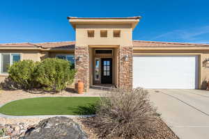 View of front facade featuring a garage, stucco siding, concrete driveway, and stone siding