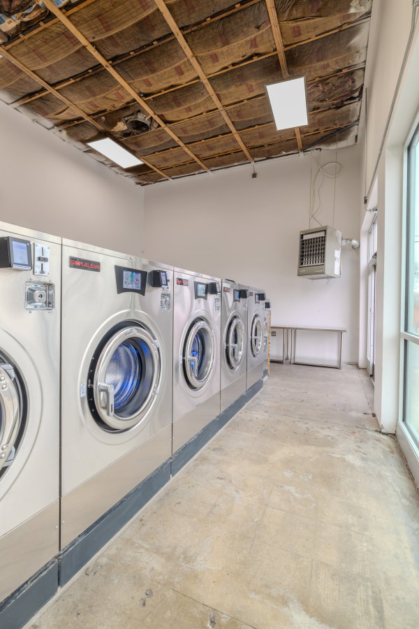 Communal laundry room with a heating unit, washing machine and dryer, a garage, and a high ceiling