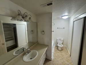 Bathroom featuring vanity, a textured ceiling, light tile patterned floors, and tub / shower combination