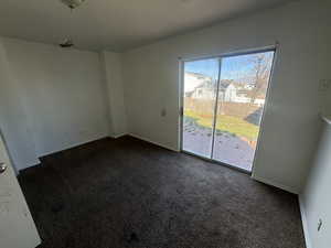 Empty room featuring baseboards and dark carpet