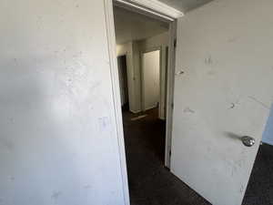 Hall featuring dark colored carpet