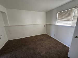 Unfurnished room featuring dark colored carpet and baseboards