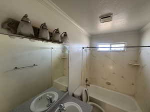 Bathroom with a textured ceiling, bathtub / shower combination, vanity, and ornamental molding