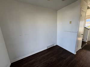 Unfurnished room featuring dark wood-style flooring and baseboards