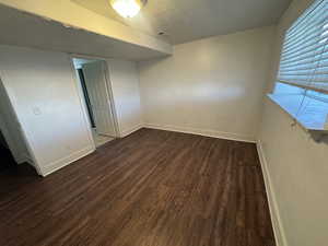 Unfurnished bedroom with a textured ceiling and dark wood-style flooring