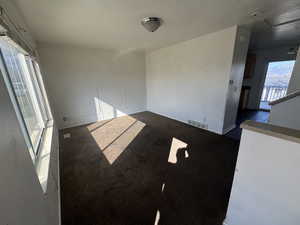 Empty room with dark colored carpet and baseboards