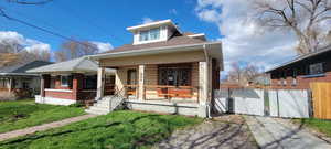 Bungalow-style house featuring a porch, a gate, roof with shingles, and brick siding