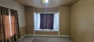 Empty room with carpet flooring and ceiling fan